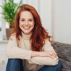 Red-haired woman in sweater sitting on couch