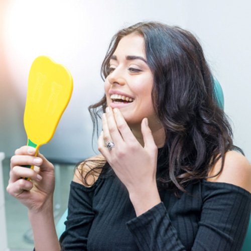 Female patient looking in dental mirror