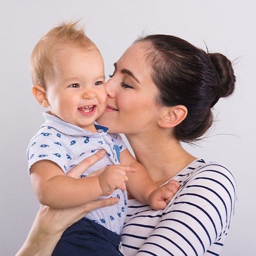 Mother kissing baby after lip and tongue tie treatment