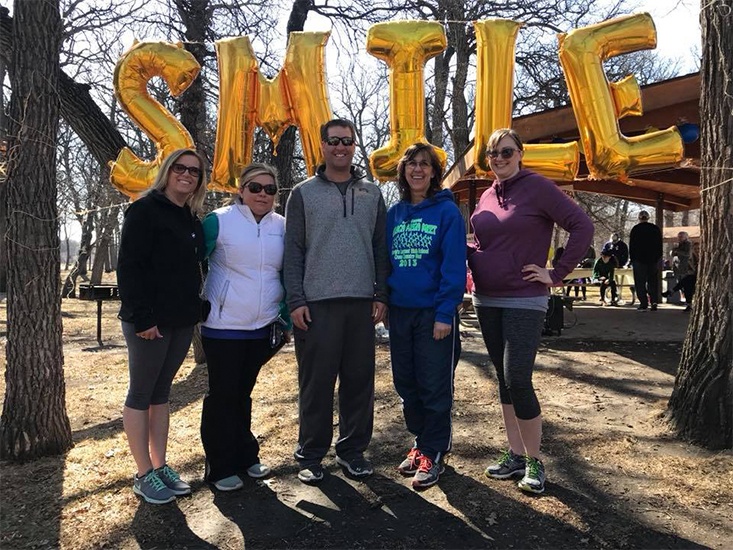 Dental team members by a sign that says smile