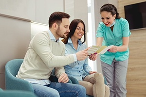 dental team member going over financing information with two patients 