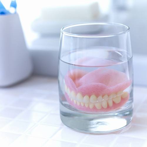 Dentures in Minot soaking in glass on bathroom counter