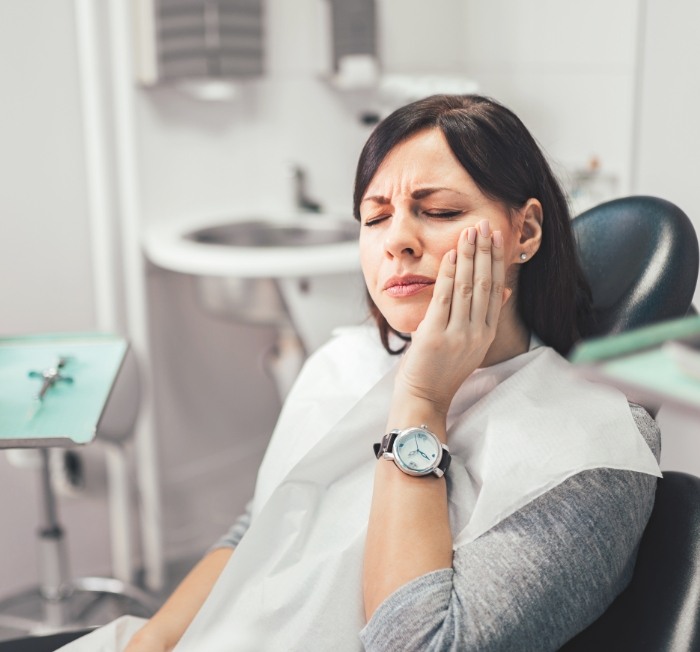 Woman in need of emergency dentistry holding jaw in pain