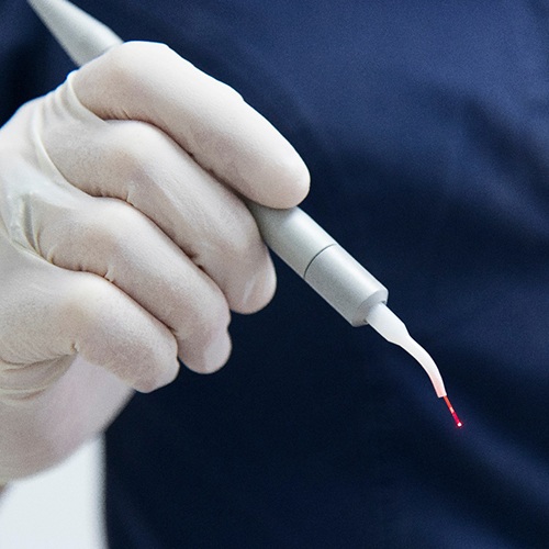 A dentist holding a soft-tissue laser