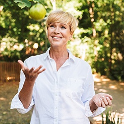 woman tossing apple while smiling