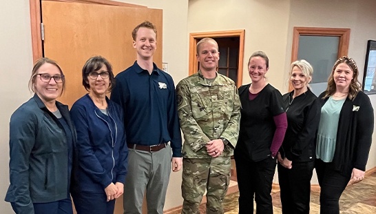 Dentist and team members posing with a man in a U S Army uniform