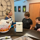 Dental team member giving a white box to two kids