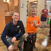Dentist smiling with young boy holding a prize bag