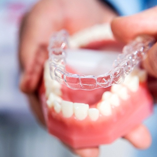 Dentist placing Invisalign tray on model of teeth