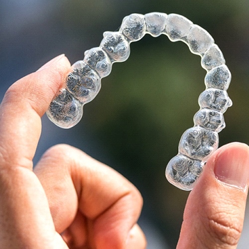 Patient holding up Invisalign trays