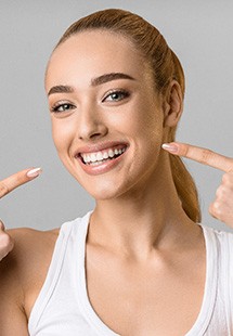 young woman pointing to smile with two fingers