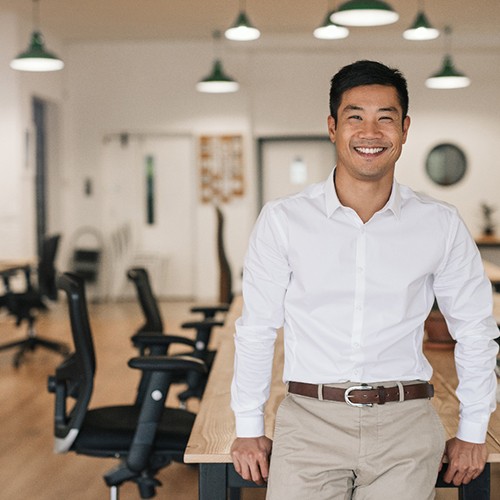 Man in business attire leaning back on a table