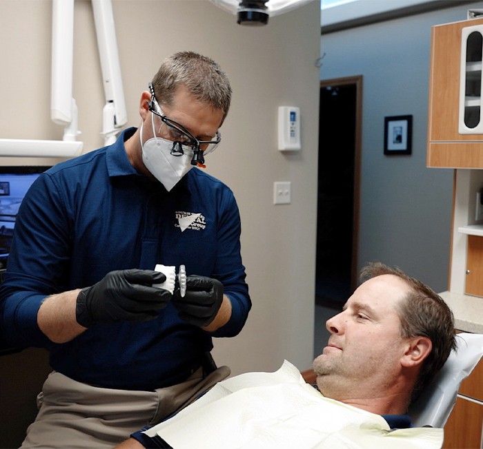 Man and woman smiling after replacing missing teeth