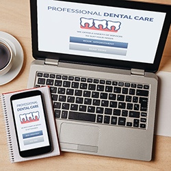 Dental insurance form on laptop and phone desk with coffee cup