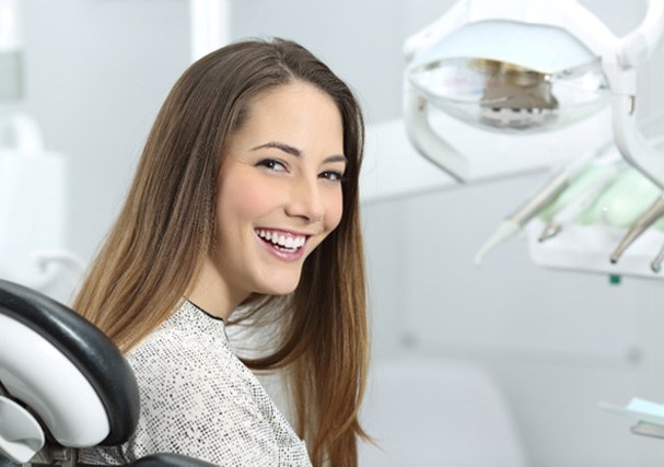 Woman smiling in dental chair after dental implant salvage in Minot, ND 