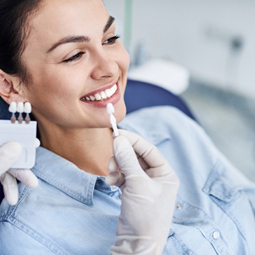 Dentist showing patient different shades for teeth whitening