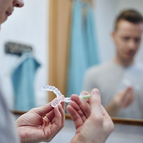 Man holding teeth whitening trays in bathroom