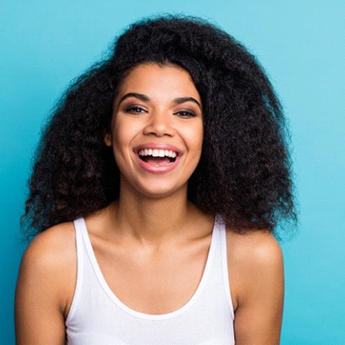 woman smiling against light turquoise background 