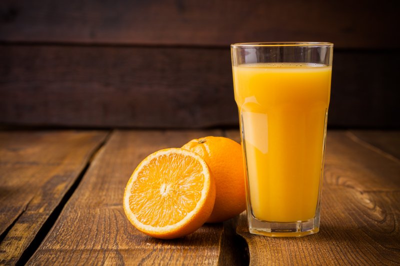 Glass of orange juice next to oranges