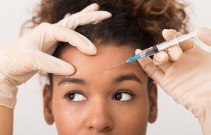 Young woman getting a BOTOX injection in her forehead