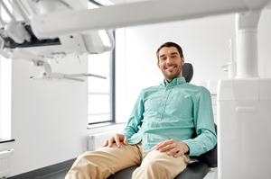 Man in a light green shirt sitting in a dental chair