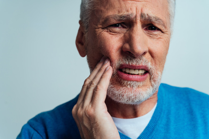 Patient rubbing cheeks due to denture sores